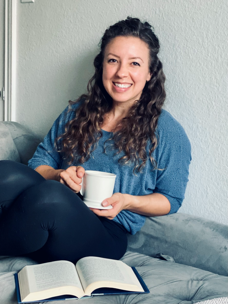 Coach Kristin sits with a mug of coffee and an open book.